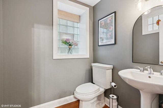 bathroom featuring toilet, baseboards, a sink, and wood finished floors
