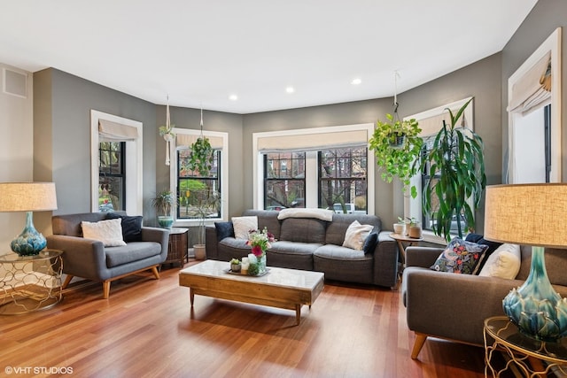 living room with recessed lighting, visible vents, a wealth of natural light, and wood finished floors