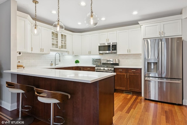 kitchen featuring light countertops, stainless steel appliances, a peninsula, and white cabinetry