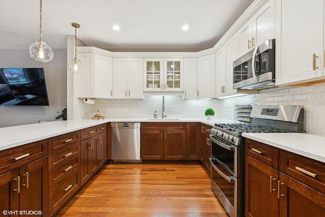 kitchen with light wood-style floors, a sink, appliances with stainless steel finishes, and white cabinets