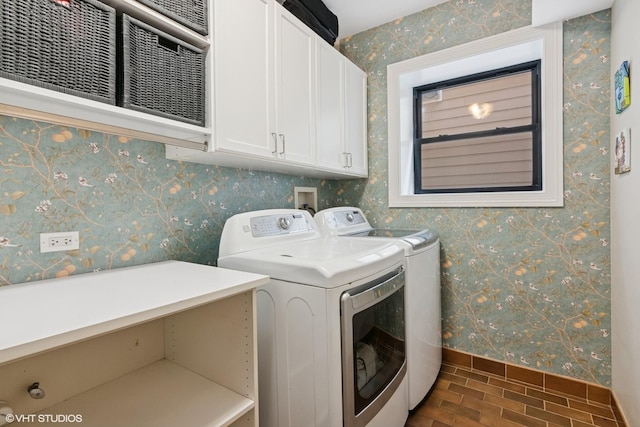 laundry room featuring washing machine and clothes dryer, baseboards, and cabinet space
