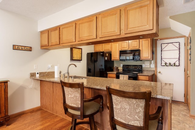 1103 Shingle Oak Ln Unit 3A, Rockford, IL 61107 - kitchen featuring a sink, black appliances, light stone counters, a peninsula, and baseboards
