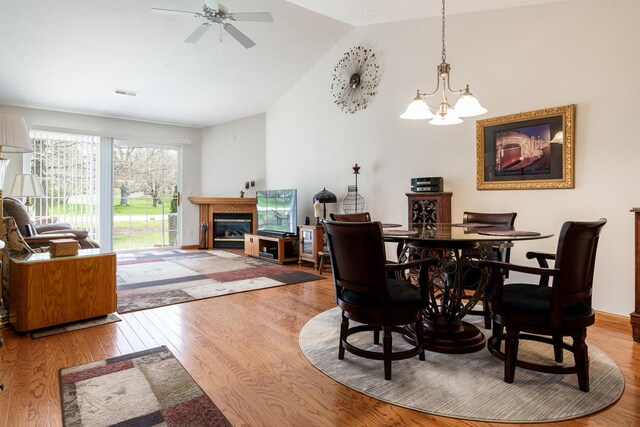 1103 Shingle Oak Ln Unit 3A, Rockford, IL 61107 - dining area featuring visible vents, a glass covered fireplace, vaulted ceiling, wood finished floors, and ceiling fan with notable chandelier