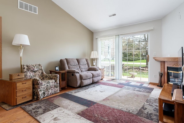 1103 Shingle Oak Ln Unit 3A, Rockford, IL 61107 - living room featuring visible vents, vaulted ceiling, wood finished floors, and a glass covered fireplace