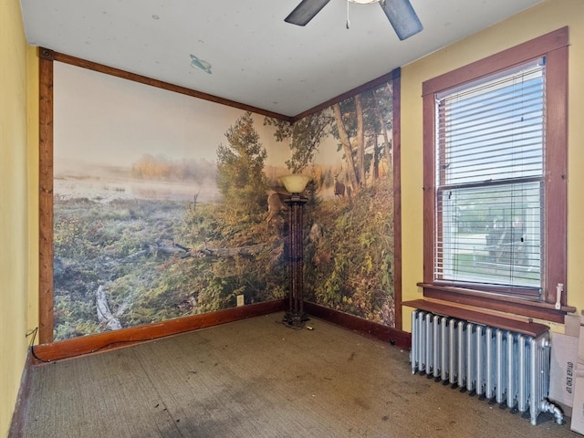 empty room with radiator heating unit, a ceiling fan, and a wealth of natural light