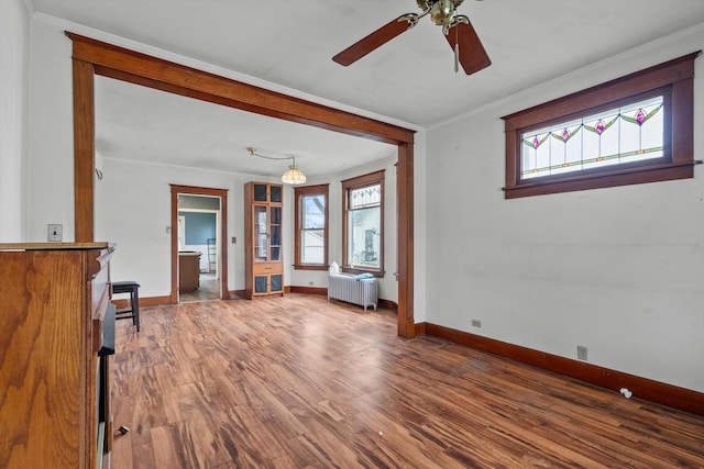 interior space featuring baseboards, ceiling fan, radiator heating unit, and wood finished floors