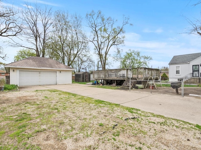 exterior space featuring fence, a wooden deck, an outdoor structure, and a garage