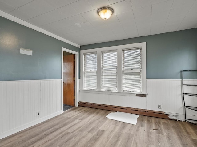 empty room with a wainscoted wall, wood finished floors, and a wealth of natural light