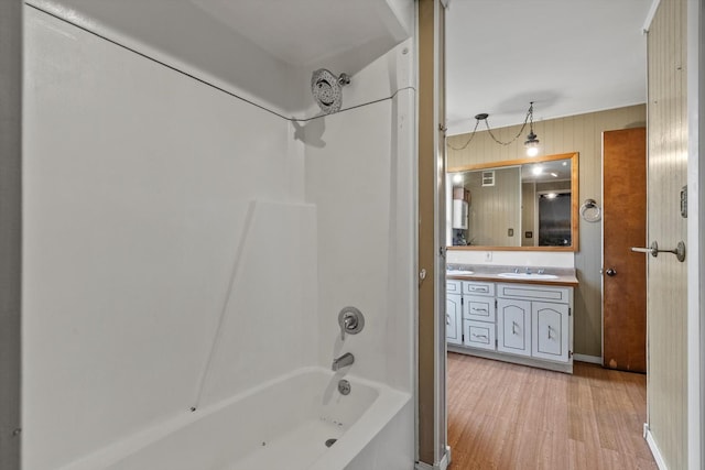 bathroom with vanity, visible vents, wood finished floors, washtub / shower combination, and wooden walls