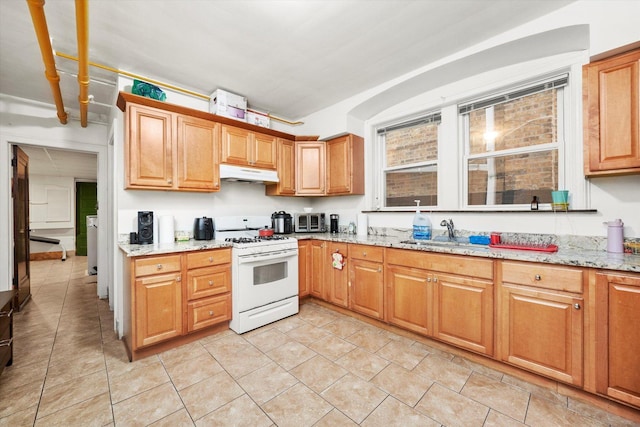 3924 W 64th Pl, Chicago, IL 60629 - kitchen featuring white gas stove, under cabinet range hood, a sink, light stone countertops, and light tile patterned flooring