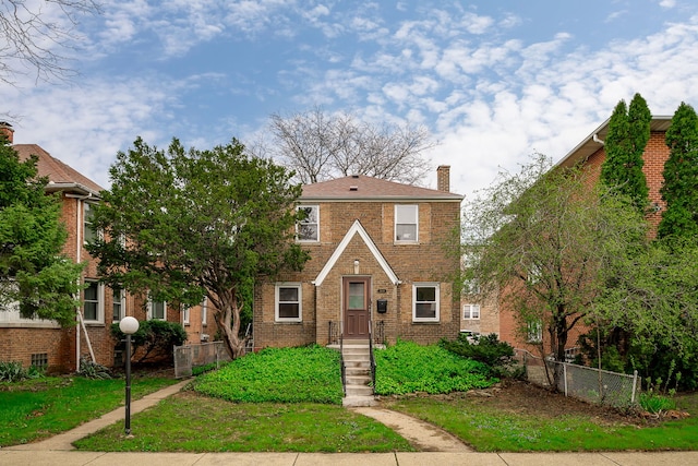 view of front of property with fence, a chimney, and brick siding