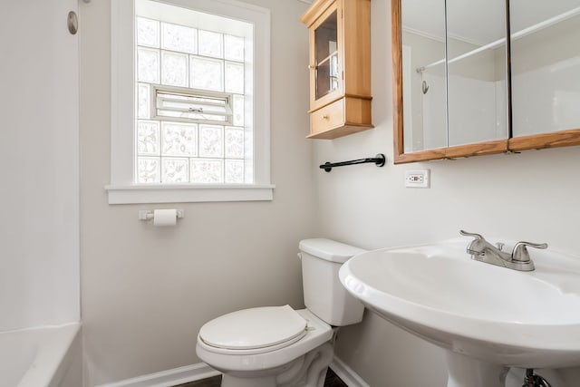 bathroom with baseboards, a sink, a healthy amount of sunlight, and toilet