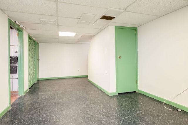 unfurnished room featuring baseboards, a drop ceiling, and visible vents