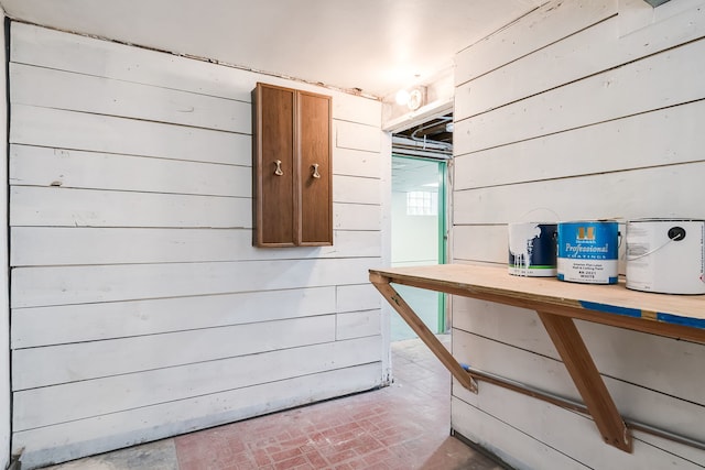 interior space with brick patterned floor and wood walls