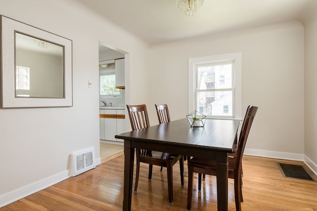 dining area featuring an inviting chandelier, baseboards, light wood-style flooring, and visible vents