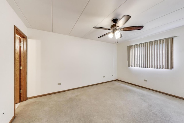 spare room featuring ceiling fan, light colored carpet, and baseboards