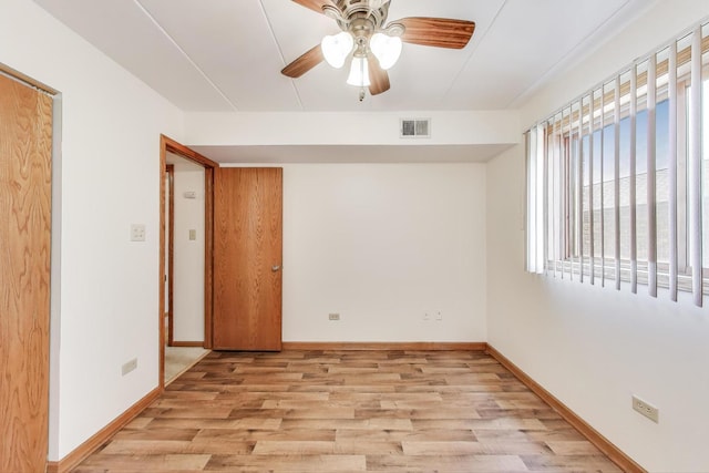 spare room featuring baseboards, a ceiling fan, light wood-style flooring, and visible vents