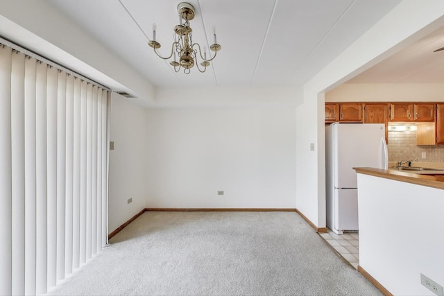 unfurnished dining area with baseboards, visible vents, light carpet, and a sink