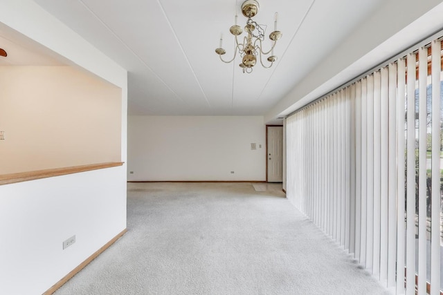 unfurnished room with baseboards, an inviting chandelier, and carpet