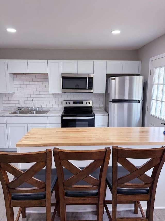 2007 E Vermont Ave, Urbana, IL 61802 - kitchen with appliances with stainless steel finishes, light countertops, backsplash, a sink, and white cabinetry