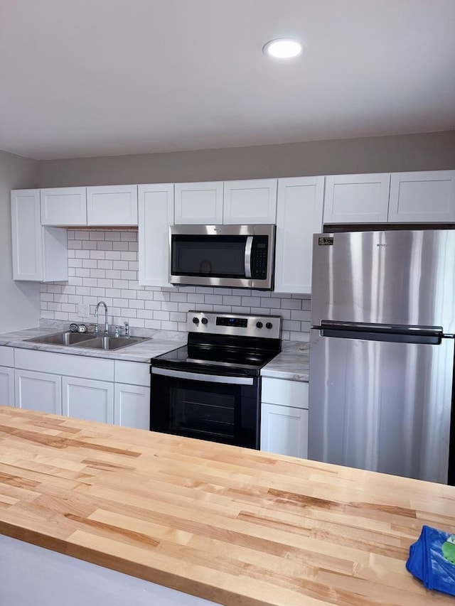 2007 E Vermont Ave, Urbana, IL 61802 - kitchen with decorative backsplash, wood counters, stainless steel appliances, white cabinets, and a sink