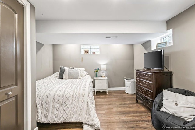 bedroom featuring baseboards, wood finished floors, and visible vents
