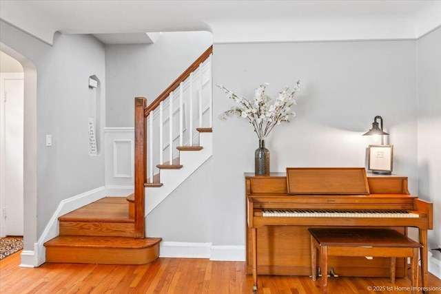 staircase featuring arched walkways and wood finished floors