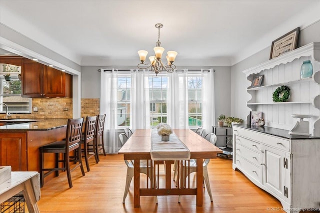 dining space with light wood-style flooring and a notable chandelier