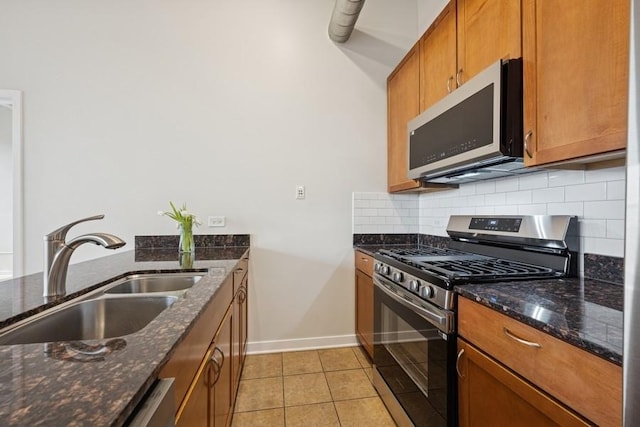 kitchen with decorative backsplash, brown cabinets, a sink, light tile patterned floors, and stainless steel appliances