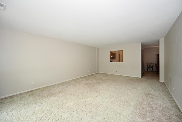 spare room with baseboards and light carpet