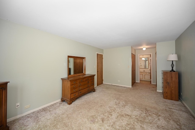 unfurnished bedroom featuring light colored carpet, baseboards, and ensuite bath