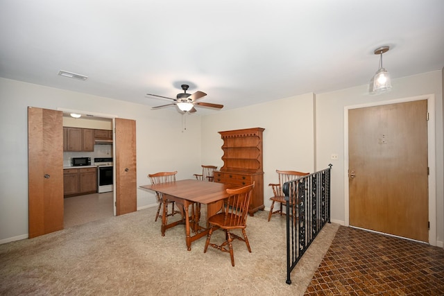 dining space featuring light colored carpet, ceiling fan, visible vents, and baseboards