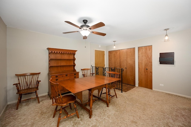 dining area featuring baseboards, a ceiling fan, and light colored carpet