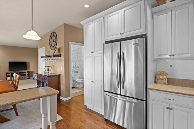 kitchen featuring tasteful backsplash, white cabinets, light countertops, freestanding refrigerator, and light wood finished floors