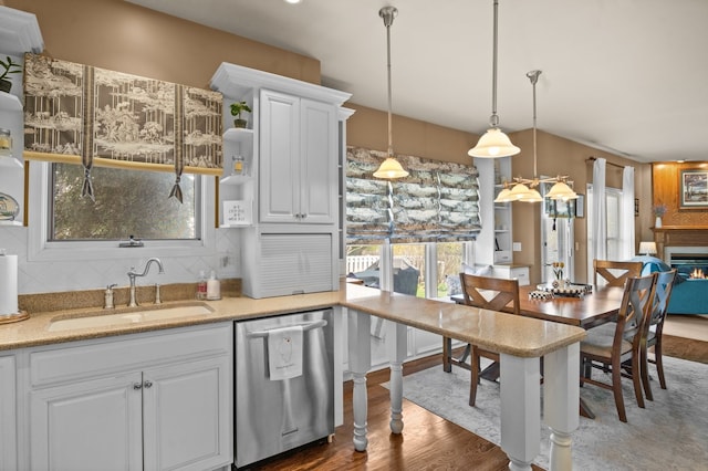 kitchen with stainless steel dishwasher, a sink, wood finished floors, and tasteful backsplash