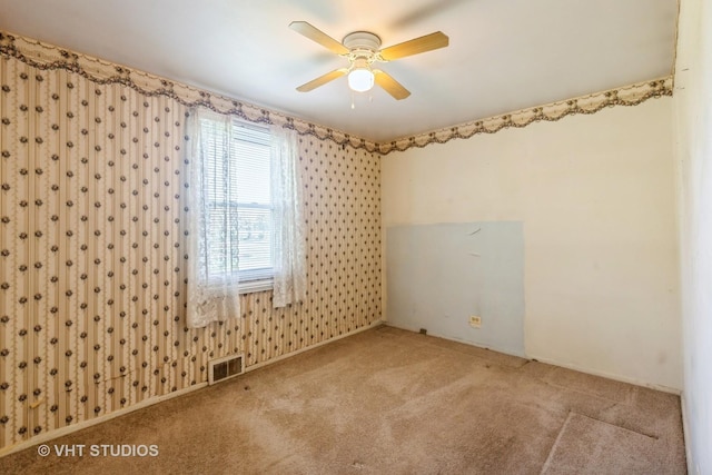 spare room with visible vents, carpet, and ceiling fan