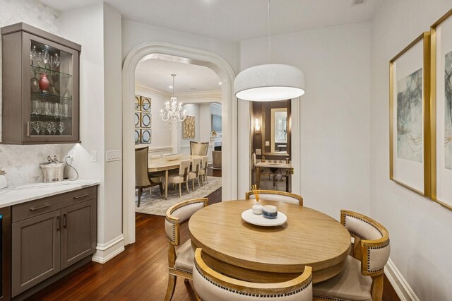 1242 N Astor St, Chicago, IL 60610 - dining space featuring dark wood-style flooring, arched walkways, baseboards, and a chandelier