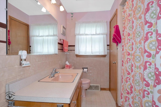 full bathroom with toilet, tile walls, vanity, curtained shower, and visible vents