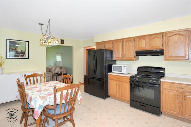 kitchen featuring light floors, under cabinet range hood, decorative light fixtures, black appliances, and light countertops