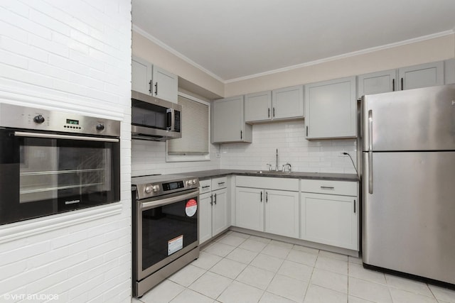 kitchen featuring dark countertops, a sink, light tile patterned floors, gray cabinetry, and appliances with stainless steel finishes