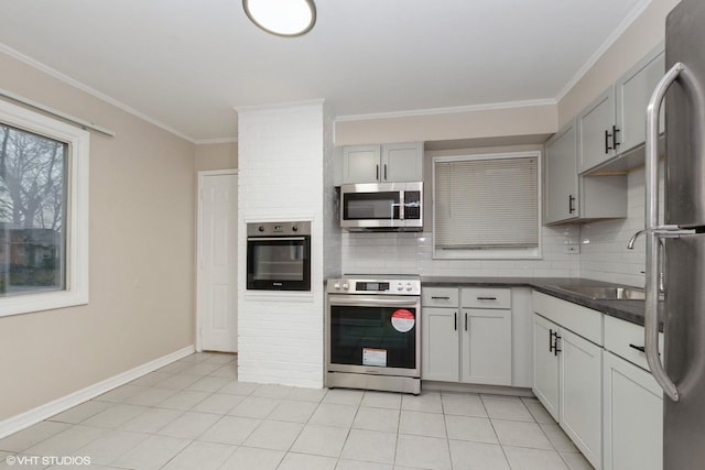 kitchen featuring a sink, stainless steel appliances, backsplash, ornamental molding, and dark countertops