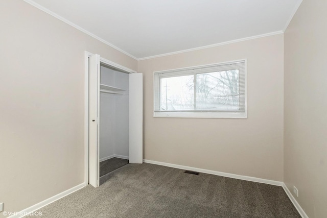 unfurnished bedroom with crown molding, a closet, carpet floors, and baseboards
