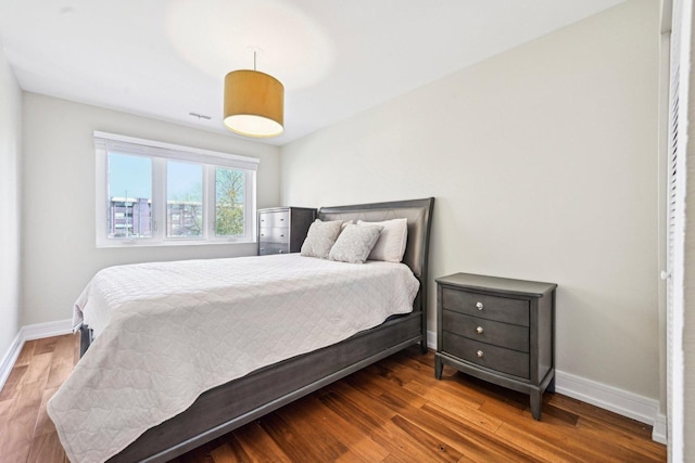 bedroom featuring baseboards, wood finished floors, and visible vents