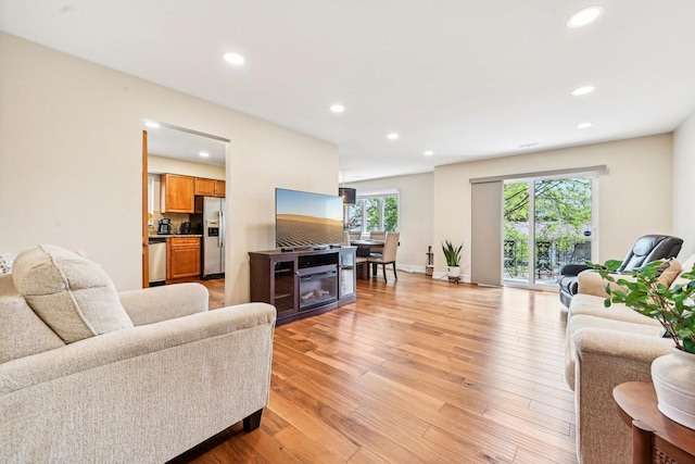 living area featuring recessed lighting, baseboards, and light wood-style floors