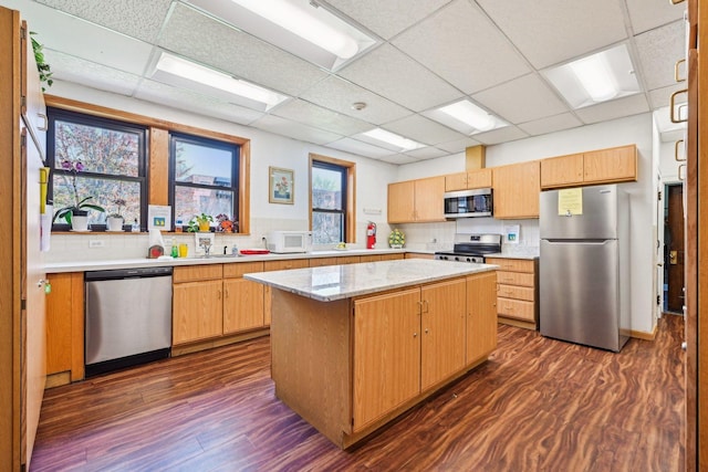 kitchen with appliances with stainless steel finishes, a paneled ceiling, and dark wood-type flooring