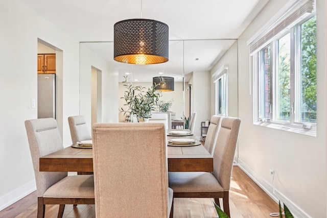 dining area with baseboards and light wood finished floors