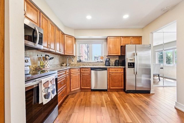 kitchen featuring light wood-style floors, a sink, appliances with stainless steel finishes, and light stone countertops