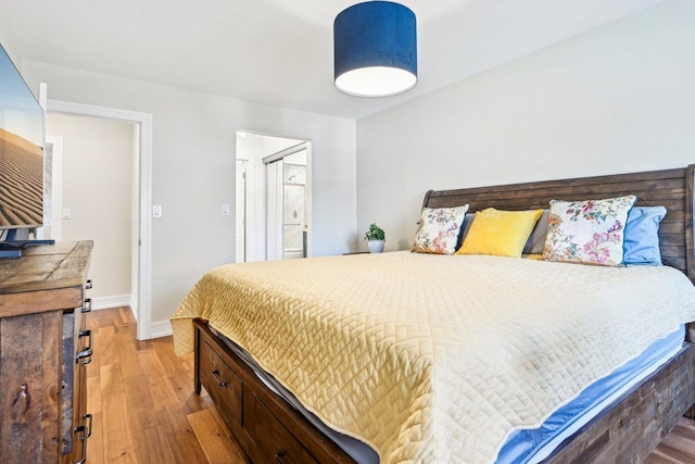 bedroom featuring baseboards, light wood-style flooring, and ensuite bathroom