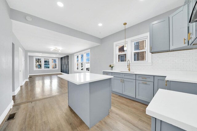 kitchen featuring open floor plan, visible vents, gray cabinetry, and a sink