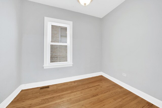 unfurnished room with visible vents, wood finished floors, and baseboards